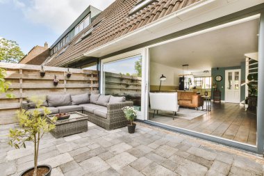 Neat paved patio with sitting area and small garden near wooden fence