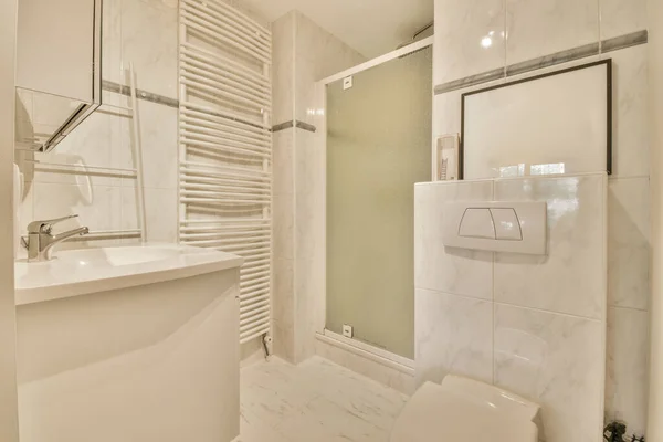 Interior of modern bathroom with rectangular mirror and clean sink near shower cabin in modern washroom