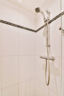 Duş muslukları cam bölmenin yanındaki fayanslı duvara bağlı ve evdeki tuvaletteki süs pervazı.