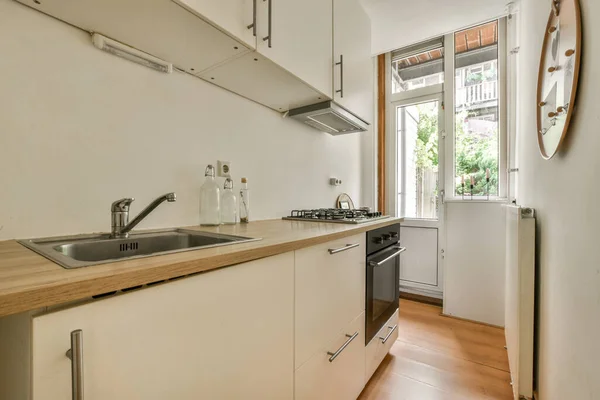 Interior of light kitchen room with balcony doors in contemporary apartment at daytime