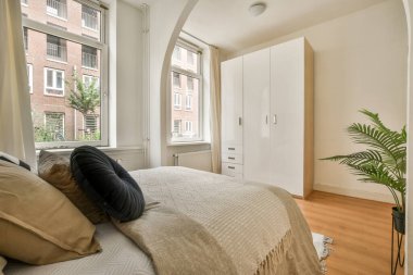 Beyaz çarşaflı rahat bir yatak ve evdeki aydınlık yatak odasına yerleştirilmiş lamba.