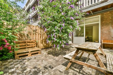 Neat powerful patio with sitting area and small garden near wooden fence