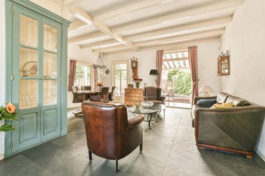 Çağdaş dairenin geniş odasındaki dinlenme odası ve mutfağın yakınındaki sandalyeli ve çiçekli masa.