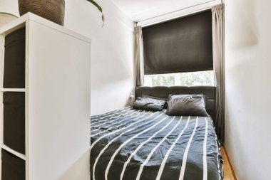 Yatak odasının iç tasarımı, yatak odası ve ahşap gardırop modern dairenin penceresinin kenarına yerleştirilmiş.