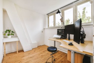 Boş tahtaya karşı bilgisayar monitörleri olan rahat sandalye ve çağdaş düz ev ofisinde ayna