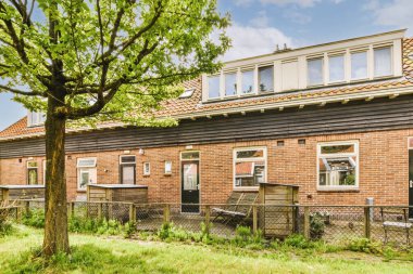 Oturma alanı ve ahşap çitlerin yanındaki küçük bahçesi olan düzgün asfaltlı bir avlu.