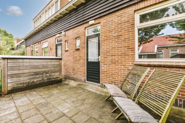 Oturma alanı ve ahşap çitlerin yanındaki küçük bahçesi olan düzgün asfaltlı bir avlu.