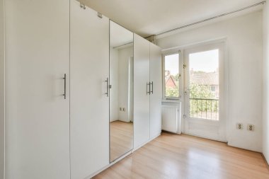 Evin penceresinin yanında rahat bir yatak ve balkon kapısı var.