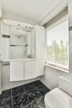 Evdeki modern tuvalette asılı duran banyo musluğu ile duvar arasındaki cam bölme.