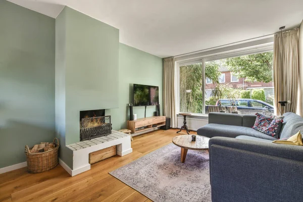 暖炉と快適なソファとカーペットを燃やすと居心地の良いリビングルームのスタイリッシュな豪華な家のインテリアデザイン日光 — ストック写真