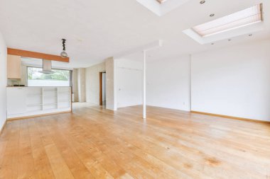 Pencereleri ve ahşap parke zemini olan boş beyaz mutfağın içi.