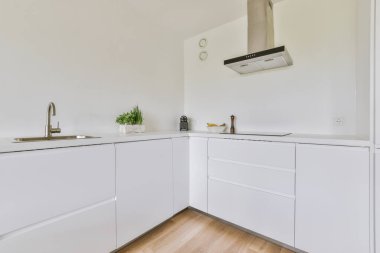 Minimalist tarzı beyaz mobilyalı, lavabolu ve sobalı bir ev mutfağı.