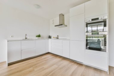 Minimalist tarzı beyaz mobilyalı, lavabolu ve sobalı bir ev mutfağı.