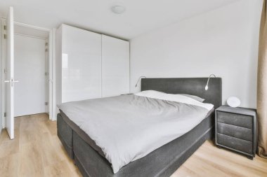 Yatak odasının iç tasarımı, yatak odası ve ahşap gardırop modern dairenin penceresinin kenarına yerleştirilmiş.