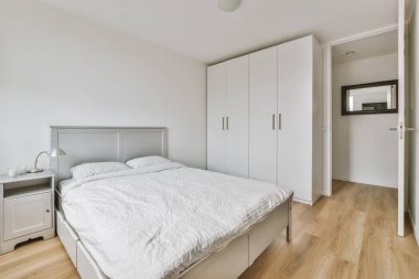 Yatak odasının iç tasarımı, yatak odası ve ahşap gardırop modern dairenin penceresinin kenarına yerleştirilmiş.