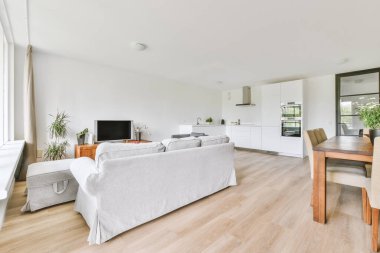 Modern apartmandaki dekorasyonlu ve televizyonlu, rahat koltuğun yanına yerleştirilmiş eski püskü ahşap masa.