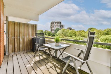 Dar tuğlalı balkon, metal parmaklıklar, tahta sandalye ve kapı.