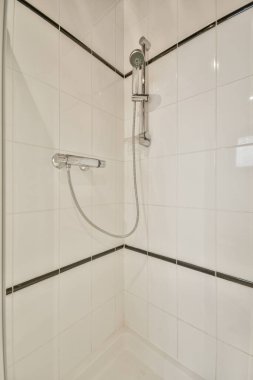 Çağdaş dairenin küçük fayanslı banyosunda lavabo ve duş arasında bulunan sifon tuvaleti