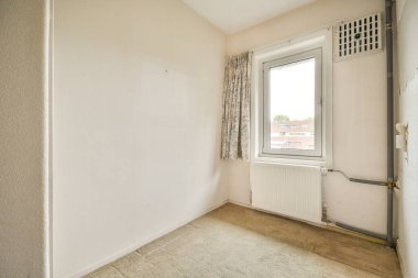 Evdeki boş ışık odasında, beyaz duvardaki plastik pencere ve radyatör.