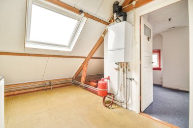 Boruları ve ölçüm cihazları olan bir apartmanın kazan dairesi. Modern dairede mühendislik iletişimi olan uzun bir oda.