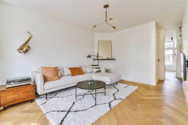 Modern apartmandaki dekorasyonlu ve televizyonlu, rahat koltuğun yanına yerleştirilmiş eski püskü ahşap masa.