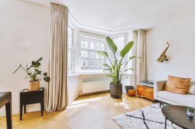 Modern apartmandaki dekorasyonlu ve televizyonlu, rahat koltuğun yanına yerleştirilmiş eski püskü ahşap masa.