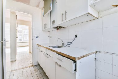 İyi organize edilmiş küçük bir ev mutfağı pencerenin altında lavabo, sobalı hafif mobilyalar ve kentsel apartmanda buzdolabı var.