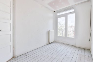 Evdeki boş ışık odasında, beyaz duvardaki plastik pencere ve radyatör.