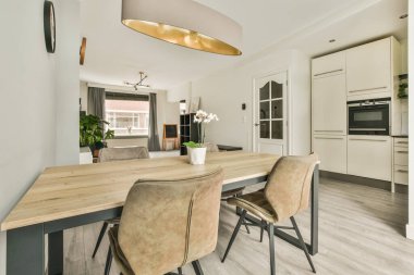 Masanın etrafına, modern dairede şık oturma odasının yemek alanında dekorasyonlar yerleştirilmiş kanepe ve koltuklar.