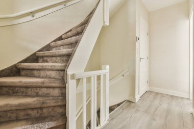 Küçük pencereli ve radyatörlü koridorun içi gündüz merdivenlerle çevrili.