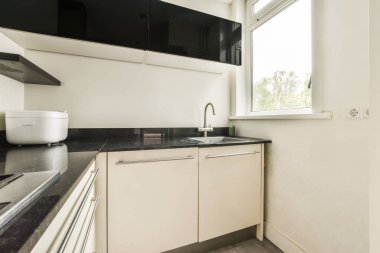 Gündüz vakti küçük pencerenin yanında modern dolap ve aletlerle donatılmış aydınlık mutfağın içi