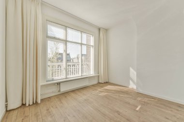 Büyük balkon pencereli, perdeli ve ahşap parke zeminli boş beyaz odanın içi.