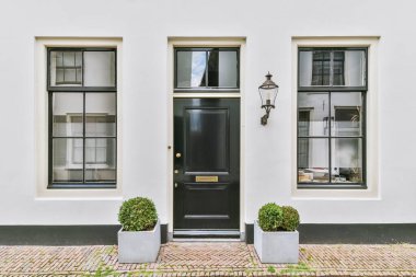 The front view of a brick building with signs, pavement and wooden doors lead to the apartment