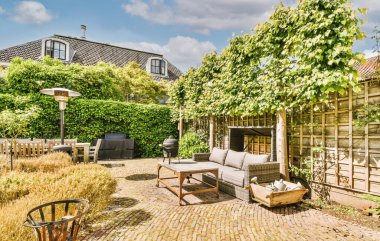 Neat paved patio with sitting area and small garden near wooden fence