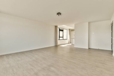 Beyaz duvarları ve parke zemini lambayla aydınlatılmış boş, modern bir daire.