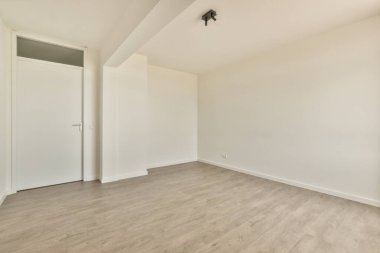 Beyaz duvarları ve parke zemini lambayla aydınlatılmış boş, modern bir daire.