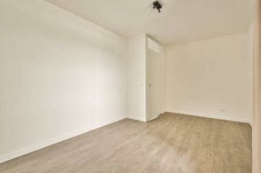 Beyaz duvarları ve parke zemini lambayla aydınlatılmış boş, modern bir daire.
