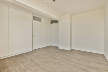 Beyaz duvarları ve parke zemini lambayla aydınlatılmış boş, modern bir daire.