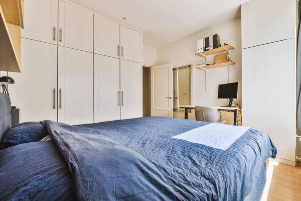 Home interior design of bedroom with bed and wooden wardrobe placed in corner near window in modern apartment