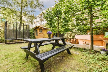 Oturma alanı ve ahşap çitlerin yanındaki küçük bahçesi olan düzgün asfaltlı bir avlu.