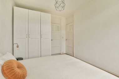 Aydınlatılmış yatak odasında lambayla rahat bir yatak ve yatağın yanında.