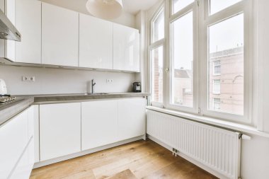 Minimalist tarzı beyaz mobilyalı, lavabolu ve sobalı bir ev mutfağı.