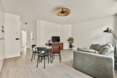 Mutfağın yakınındaki açık oturma odasındaki şöminenin yanındaki zarif avizenin altında yumuşak yastıklı büyük bir kanepe.