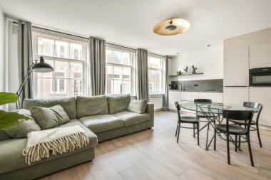 Mutfağın yakınındaki açık oturma odasındaki şöminenin yanındaki zarif avizenin altında yumuşak yastıklı büyük bir kanepe.