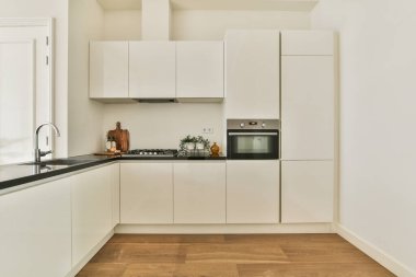 Çağdaş dairenin geniş odasındaki dinlenme odası ve mutfağın yakınındaki sandalyeli ve çiçekli masa.