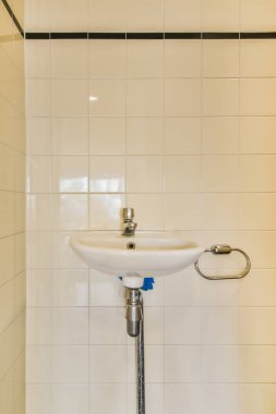 Interior of narrow restroom with sink and wall hung toilet with tile and checkered floor