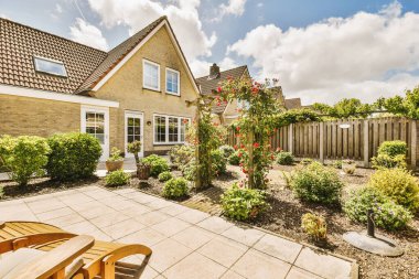 Oturma alanı ve ahşap çitlerin yanındaki küçük bahçesi olan düzgün asfaltlı bir avlu.