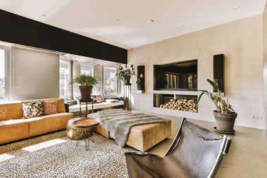 Geniş pencereli, beyaz duvarlı, rahat kanepe ve halı döşeli, geniş oturma odasının şık iç tasarımı.