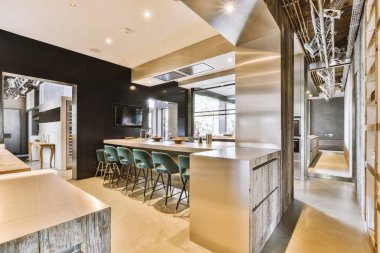 Mutfağın yakınındaki açık oturma odasındaki şöminenin yanındaki zarif avizenin altında yumuşak yastıklı büyük bir kanepe.