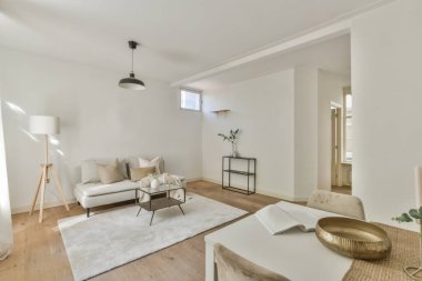 Çağdaş dairenin geniş odasındaki dinlenme odası ve mutfağın yakınındaki sandalyeli ve çiçekli masa.